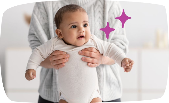 Un bebé sostenido por un adulto por detrás